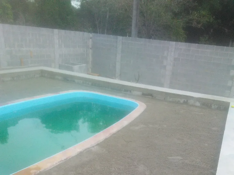 Piscina residencial com piso externo e muro claro